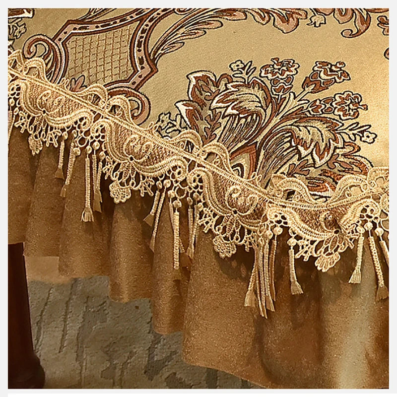 Motif floral décoratif en dentelle dorée sur un tissu de couleur ocre, avec des éléments floraux et des franges pendant à la bordure.