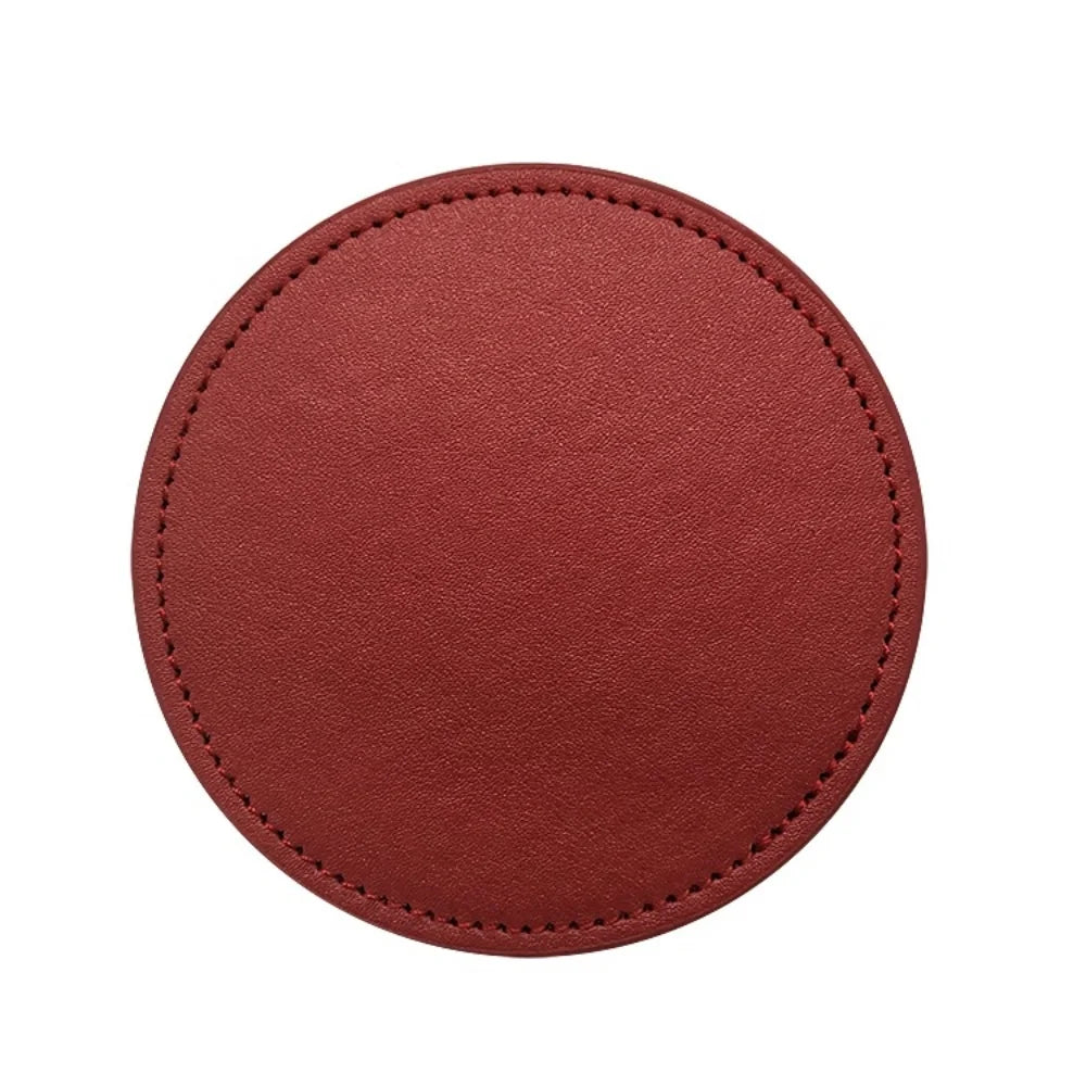 Dessous de verre rond en cuir de couleur rouille avec surpiqûres.