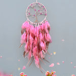 Un attrape-rêves décoratif rose suspendu, orné de plumes et de cristaux scintillants, créant une atmosphère whimsique et féerique.