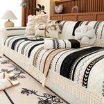 Un lit aux motifs ethniques en noir et blanc avec des franges élégantes, créant une atmosphère chaleureuse et rustique dans la chambre.