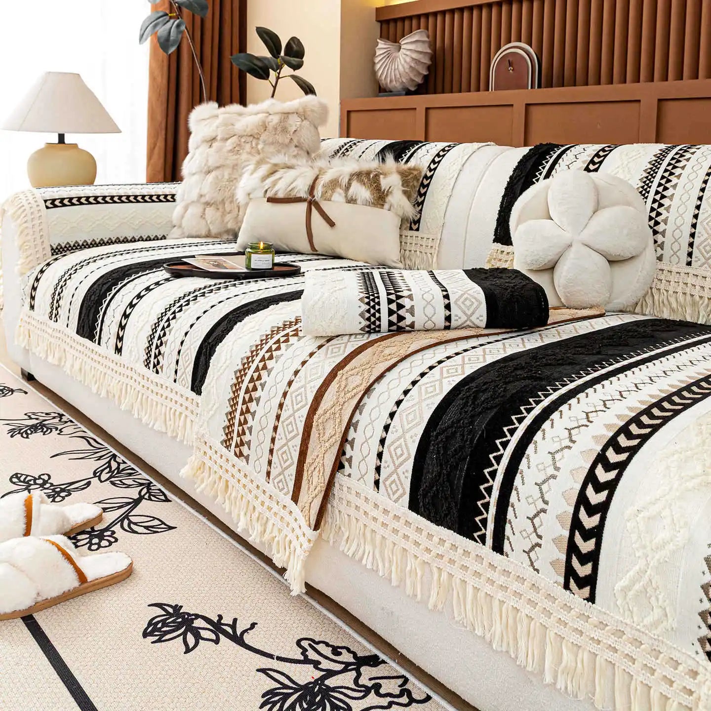 Un lit aux motifs ethniques en noir et blanc avec des franges élégantes, créant une atmosphère chaleureuse et rustique dans la chambre.