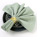Élégante vaisselle noire et dorée avec des serviettes en soie vert menthe soigneusement pliées, créant une présentation raffinée et esthétique.