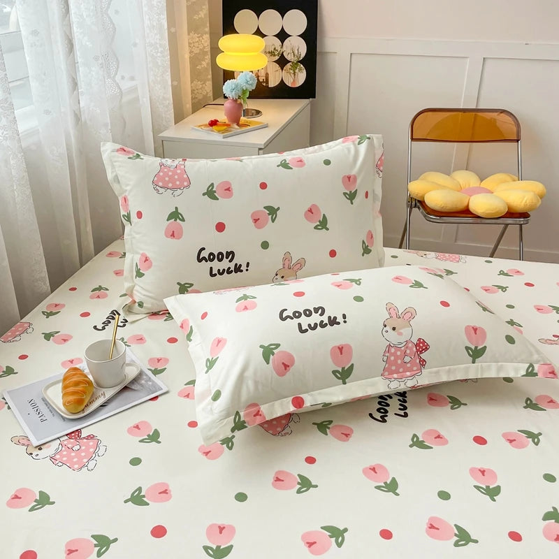 L'image montre une chambre à coucher décorée dans un style doux et coloré, avec des motifs de fleurs et de lapins sur les draps et les oreillers, ainsi qu'un plateau de viennoiseries sur une étagère. L'ensemble crée une atmosphère chaleureuse et accueillante.