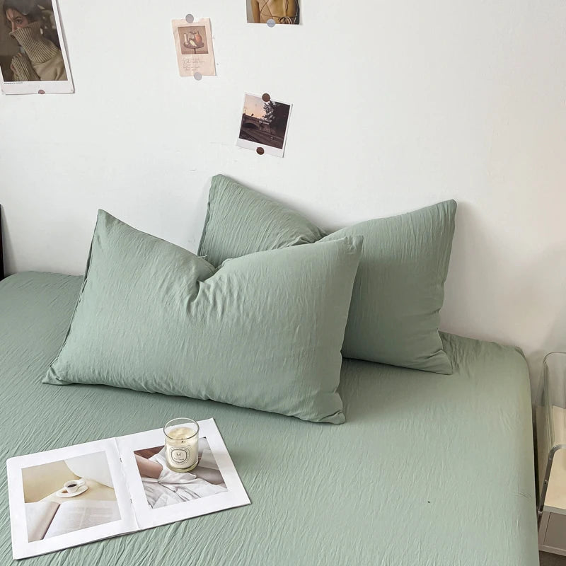 Une photo d'un canapé vert pastel confortable, avec des coussins assortis et une bougie sur une petite table basse, dans un environnement décoré de façon minimaliste.