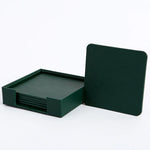 Un ensemble de sous-verres carrés de couleur verte, empilés et rangés dans un support assorti.