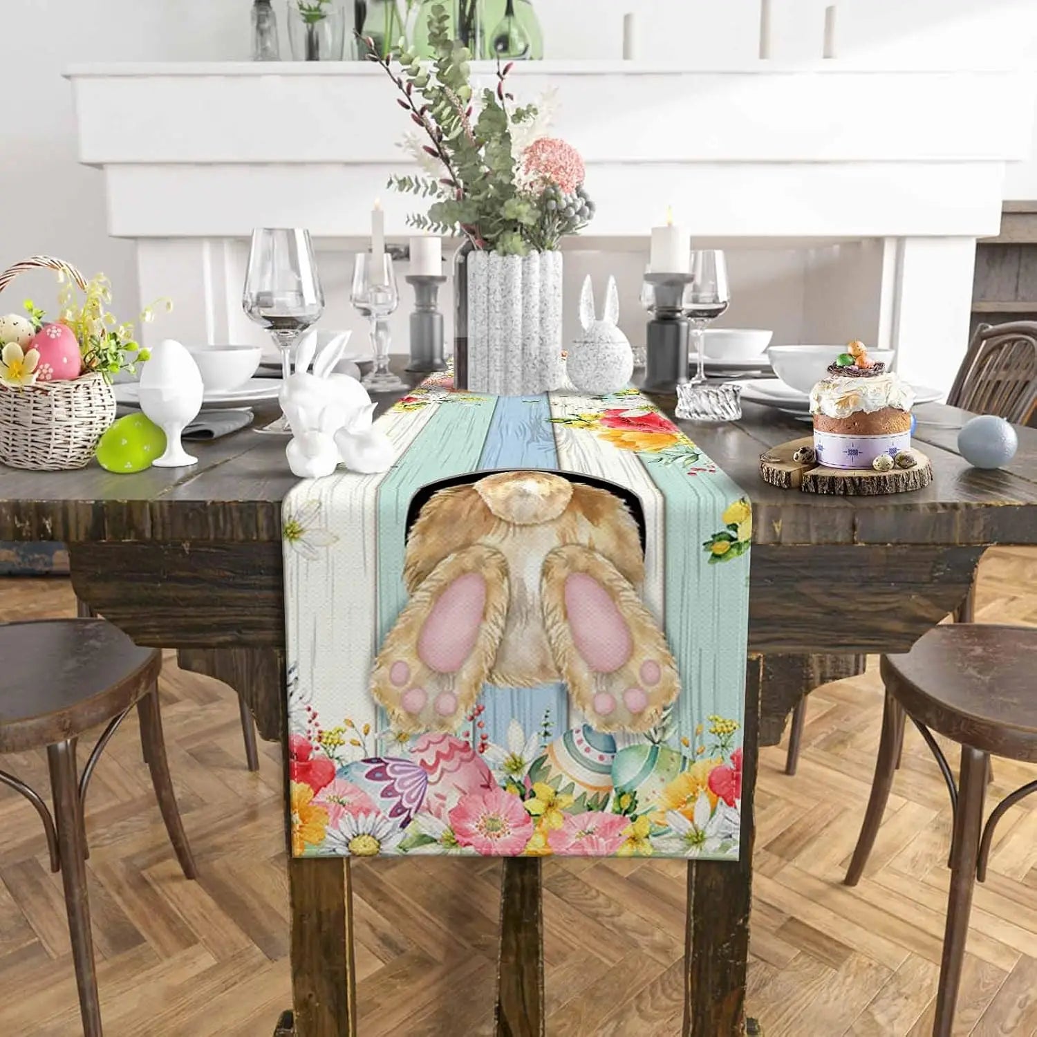 Table élégamment décorée pour Pâques, avec un chemin de table fleuri, des fleurs, des lapins en céramique et d'autres éléments de décoration festive.