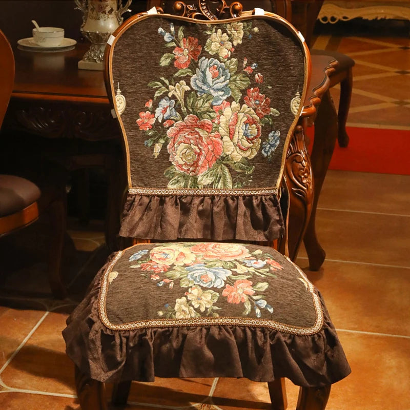 Une chaise ancienne avec un dossier et un coussin ornés de motifs floraux colorés sur un fond sombre, créant une ambiance vintage et élégante.