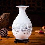 Vase en porcelaine blanche décoré d'un paysage hivernal avec des maisons et des montagnes enneigées.