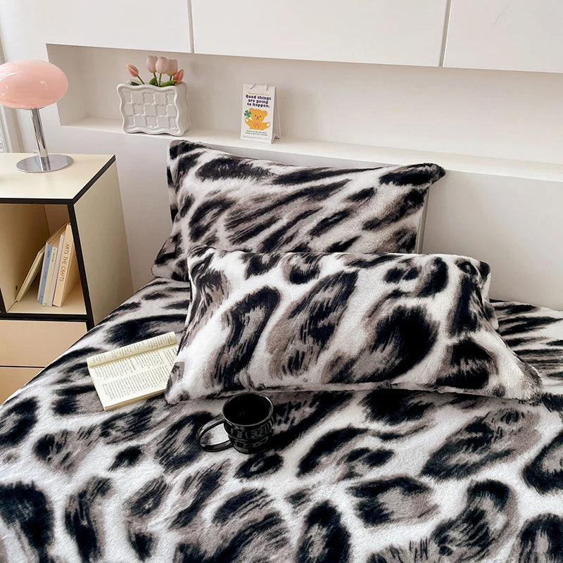 Ensemble de couette et d'oreillers en peluche avec motif zébré noir et blanc, posé sur un lit dans un intérieur confortable avec des éléments de décoration.