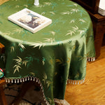 Tissu décoratif vert avec motifs de bambous, posé sur une table en bois avec un cadre photo.