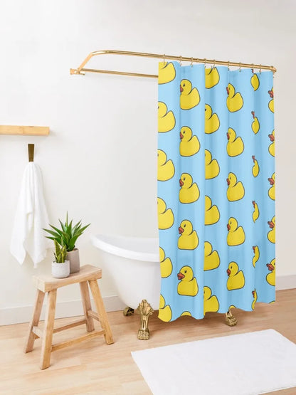 Autre vue de la salle de bain présentant un tabouret en bois, des serviettes blanches accrochées au mur et le même rideau de douche bleu à canards jaunes, créant une ambiance ludique.