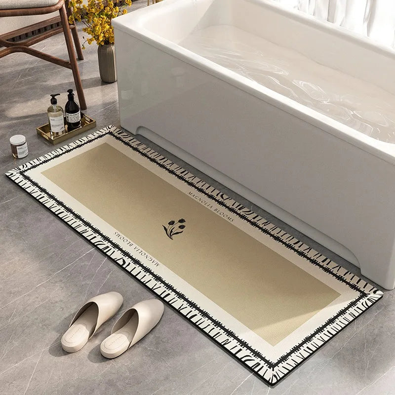 Un élégant tapis de bain blanc et noir décoré de motifs botaniques, placé devant une baignoire blanche dans une salle de bain moderne et épurée.