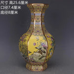 Un vase oriental en porcelaine ornée de motifs floraux et animaux sur un fond jaune éclatant.