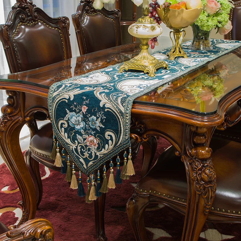 Une table de salle à manger élégante avec des chaises en bois sculptées et un chemin de table décoratif de style oriental, orné de motifs floraux et de glands décoratifs.