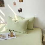 Un lit douillet avec des oreillers verts pastel, décoré de quelques photos accrochées au mur pour une ambiance chaleureuse et apaisante.