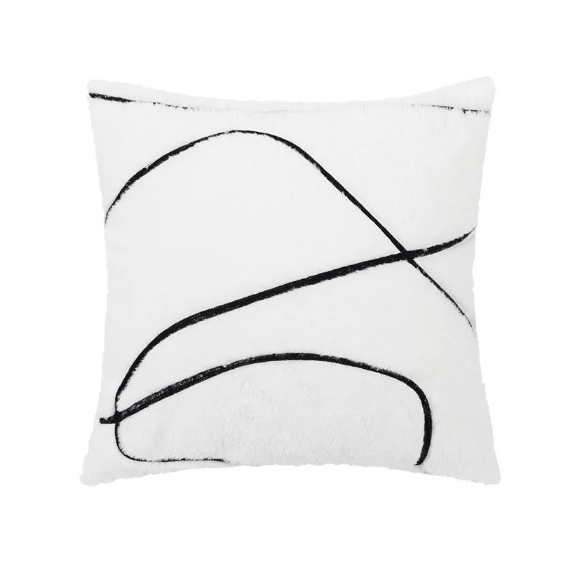 Coussin moelleux en blanc et noir avec des lignes incurvées abstraites.