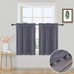 Rideaux courts gris en velours à pompons décorant une fenêtre, avec vue sur un mur clair et un mobilier de style scandinave.