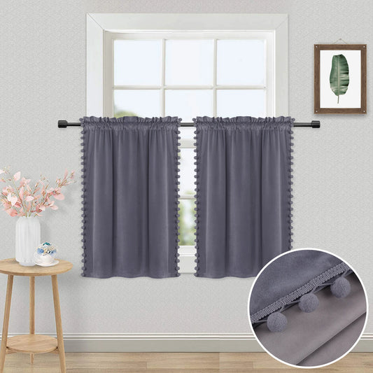 Rideaux courts gris en velours à pompons décorant une fenêtre, avec vue sur un mur clair et un mobilier de style scandinave.