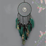 Captivant attrape-rêves noir avec une collection de plumes vertes, de perles et de motifs géométriques, créant une œuvre d'art fascinante et ornementale.