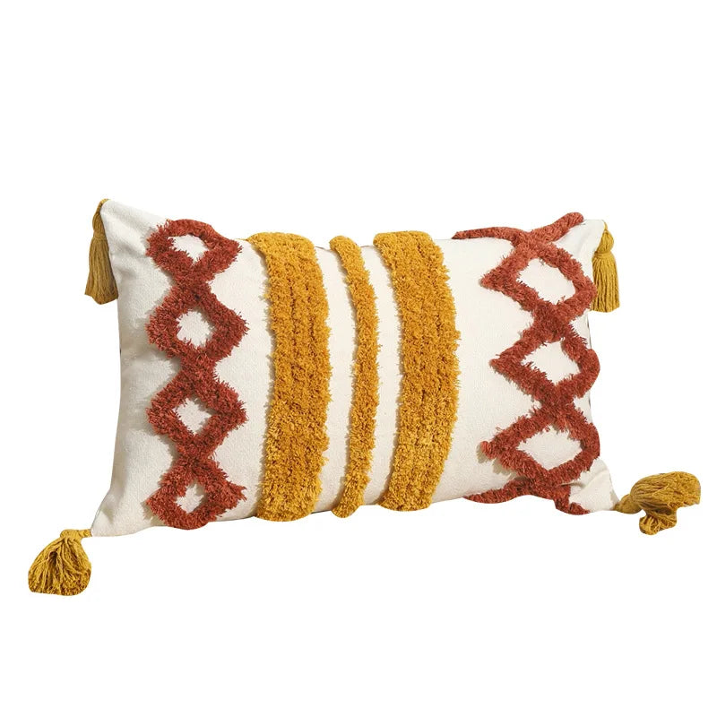 Coussin décoratif en coton blanc et jaune moutarde avec motifs graphiques et franges colorées.