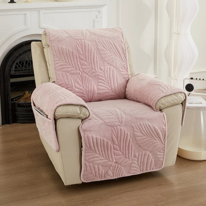 Fauteuil confortable avec un motif de feuilles en relief sur un tissu rose pâle, placé dans un intérieur cosy avec une cheminée.