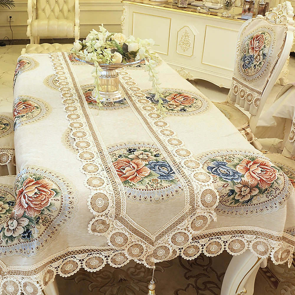 Cette somptueuse nappe de table ornée de motifs floraux et de dentelle crème crée une ambiance élégante et raffinée, reflétant le style décoratif luxueux de cette pièce.