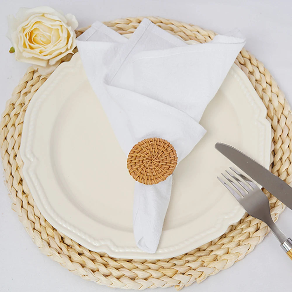 Une élégante vaisselle blanche et ronde posée sur un plateau tressé doré, rehaussée d'une ravissante fleur blanche, évoque une ambiance apaisante et raffinée.