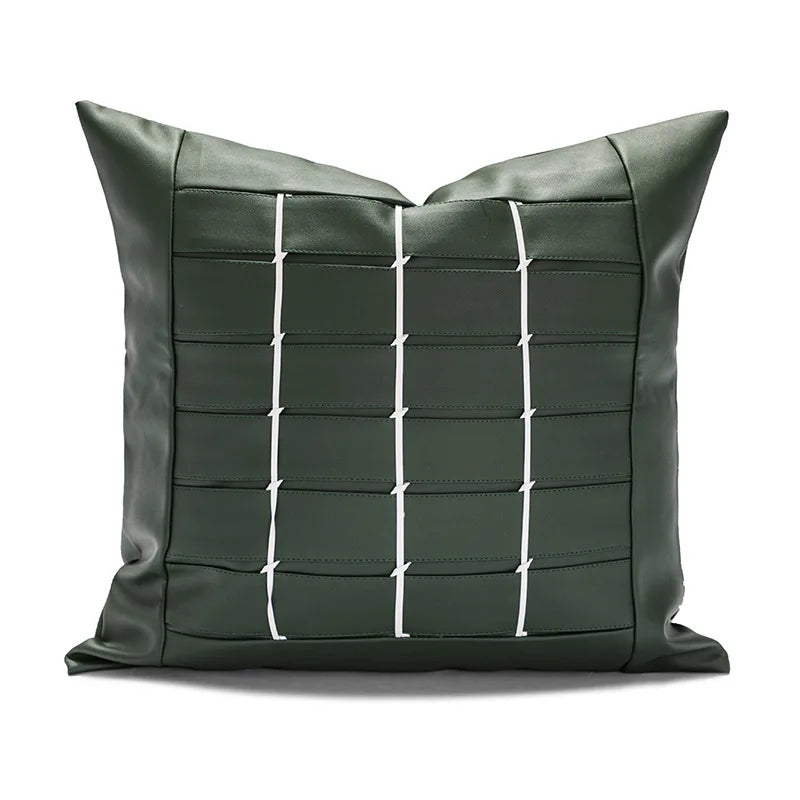 Oreiller décoratif en cuir vert foncé avec motif carré blanc.