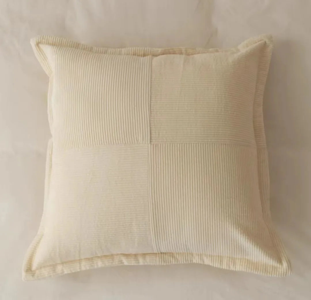 Coussin décoratif en coton avec motif rayé sur un fond crème, offrant une texture douce et une touche élégante pour la décoration d'intérieur.