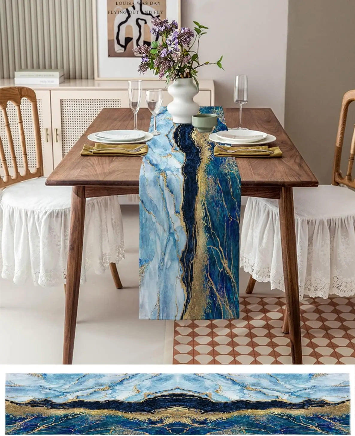 Une table élégante avec une nappe de table aux motifs colorés et dorés, décorée de fleurs dans un vase blanc et de verres à vin. Le style moderne et raffiné de la salle à manger est complété par un carrelage aux motifs géométriques.