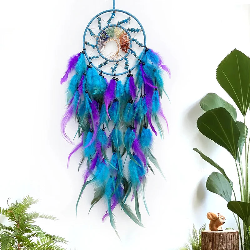 Un attrapeur de rêves coloré décoré de plumes bleu, violet et turquoise suspendu dans un décor naturel.