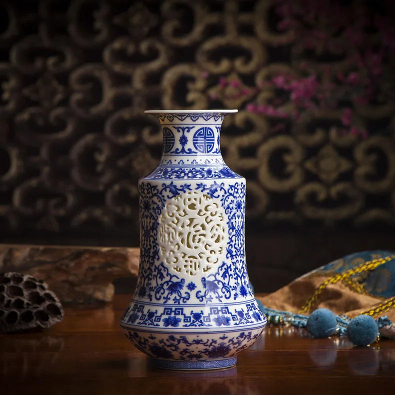 Vase en porcelaine bleue et blanche orné de motifs floraux et géométriques élégants, posé sur une surface en bois avec des accessoires décoratifs.