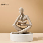 statue décorative résine figure humaine assise livre ouvert beige clair doré textures abstraites moderne