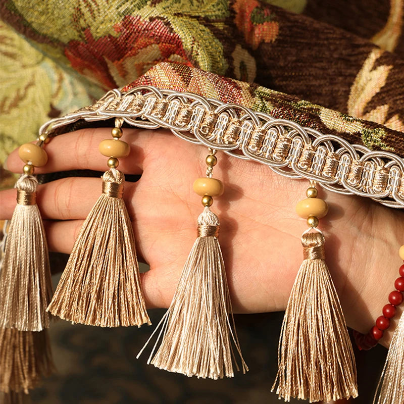 Une ceinture ornée de franges dorées et de perles sur un fond d'étoffe élégante.