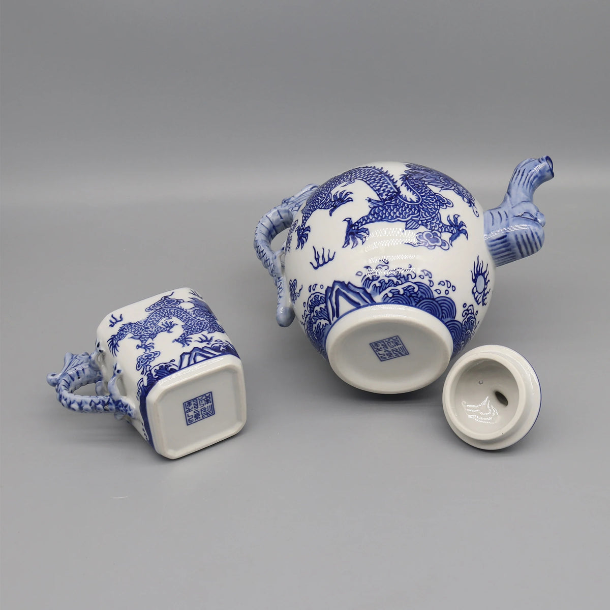 Théière et tasse en céramique décorées de motifs bleus et blancs représentant des dragons, offrant un style authentique asiatique.
