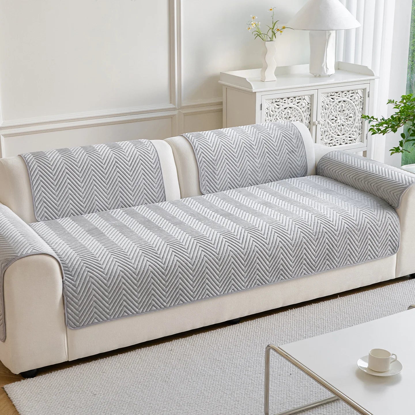 Un canapé confortable avec un motif géométrique gris et blanc, posé dans un bel intérieur lumineux avec des décorations élégantes.