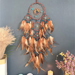 Un beau capteur de rêves décoratif suspendu avec des plumes de couleur ocre, des perles et des fleurs séchées, offrant un accent bohème charmant à l'espace.