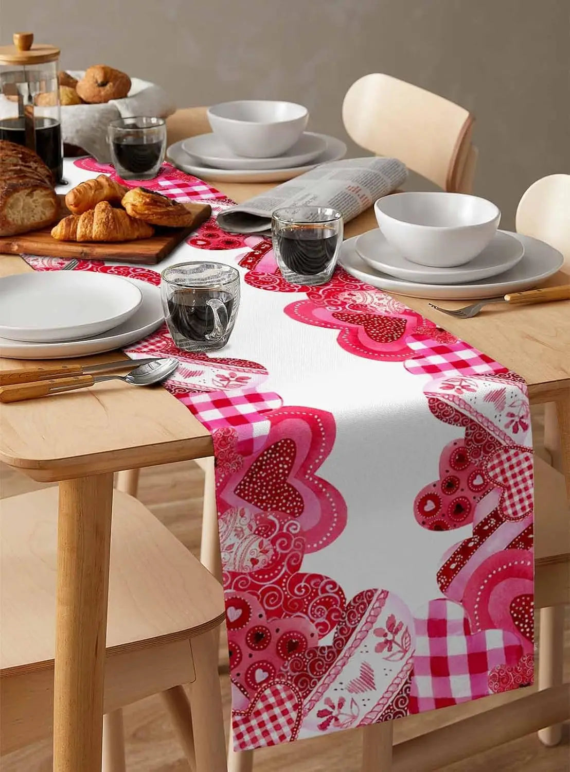 Cette image montre une table élégante et conviviale, avec des assiettes, des tasses, des croissants et un chemin de table en couleurs vives et motifs variés, suggérant une ambiance chaleureuse et accueillante.