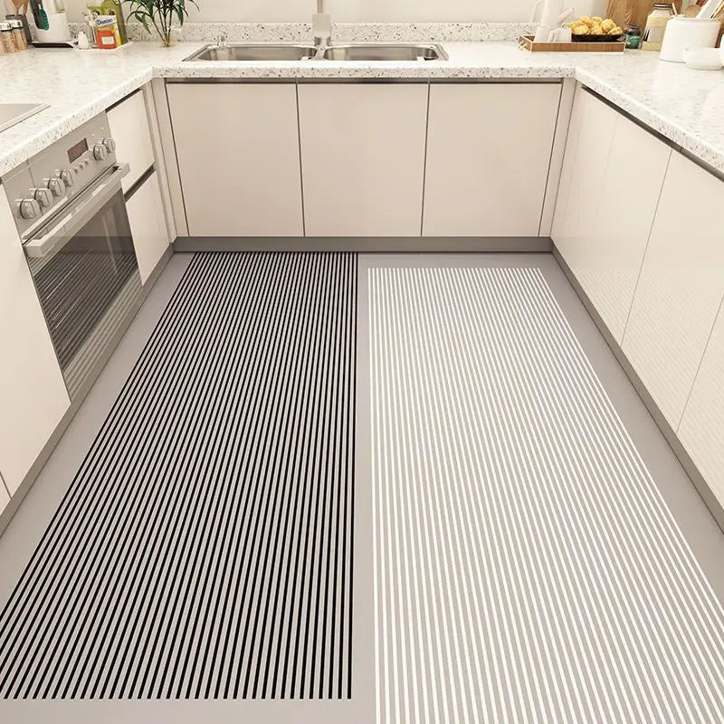 L'image montre un design de sol de cuisine moderne avec des carreaux noirs et blancs aux rayures distinctes, offrant un contraste élégant avec les armoires grises et le plan de travail en granite.