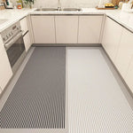 L'image montre un design de sol de cuisine moderne avec des carreaux noirs et blancs aux rayures distinctes, offrant un contraste élégant avec les armoires grises et le plan de travail en granite.