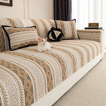 Un chat blanc assis sur un canapé avec un motif géométrique beige et brun