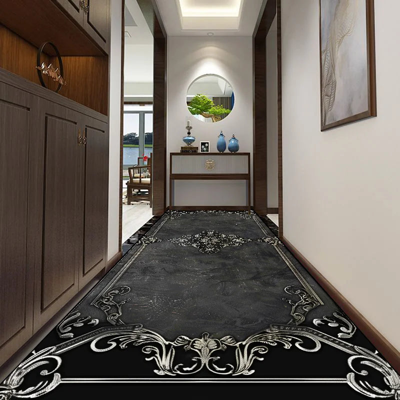 Élégant couloir avec un sol en carrelage noir orné de motifs décoratifs et un miroir en forme d'arche qui reflète la végétation à l'extérieur, créant une atmosphère chaleureuse et raffinée.