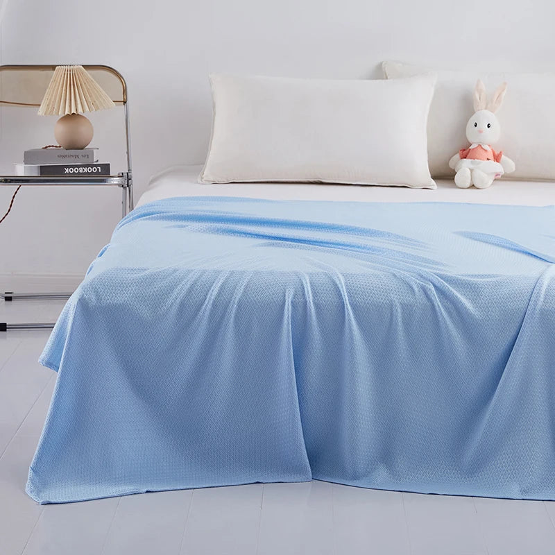 Lit simple avec une couverture bleue pastel et des accessoires décoratifs, créant une atmosphère douce et relaxante dans la chambre.