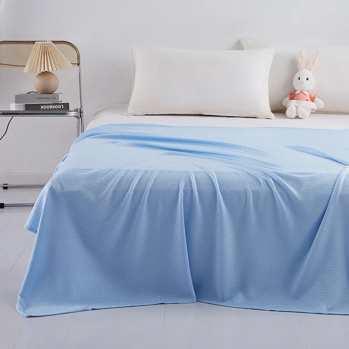 Lit simple avec une couverture bleue pastel et des accessoires décoratifs, créant une atmosphère douce et relaxante dans la chambre.