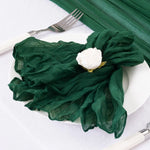 Une assiette blanche avec une serviette en tissu vert émeraude ornée d'une élégante fleur blanche.