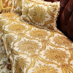 Coussin décoratif en velours de couleur doré avec un motif floral vintage sur un design de style baroque.