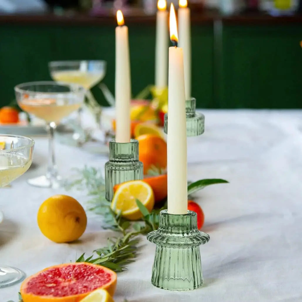 Une table élégante avec des bougies allumées, des verres de cocktail, des fruits frais et une composition florale apportant une touche chaleureuse et festive à cette scène.