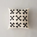 Coussin décoratif blanc et noir avec des motifs de croix.