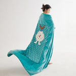 Une jeune femme vêtue d'un kimono bleu turquoise décoré d'un motif de nuages et d'un personnage aux grands yeux.