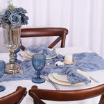 Une magnifique table dressée avec des fleurs bleues, des photophores et de la vaisselle élégante sur un fond blanc.